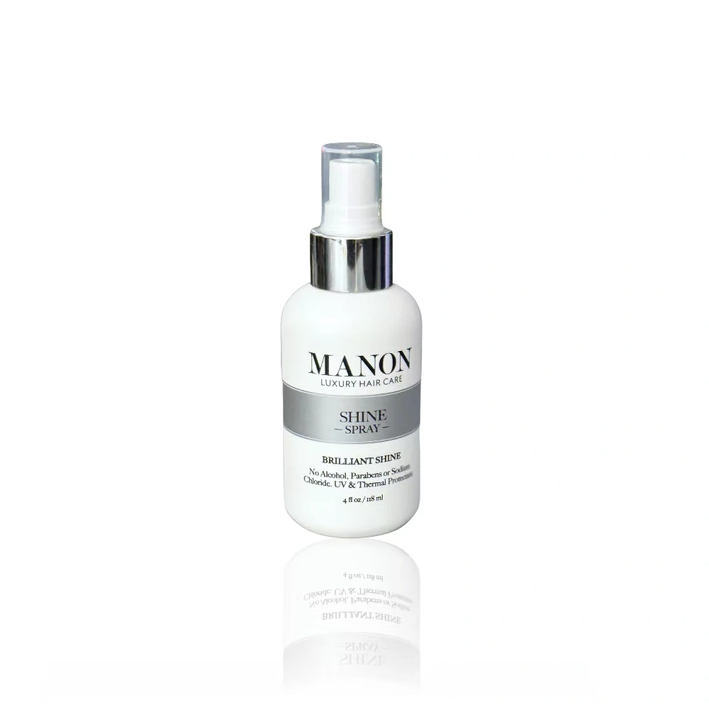 A white bottle of Manon Brilliant Shine Spray, a luxury hair care product, displayed against a clean white background.