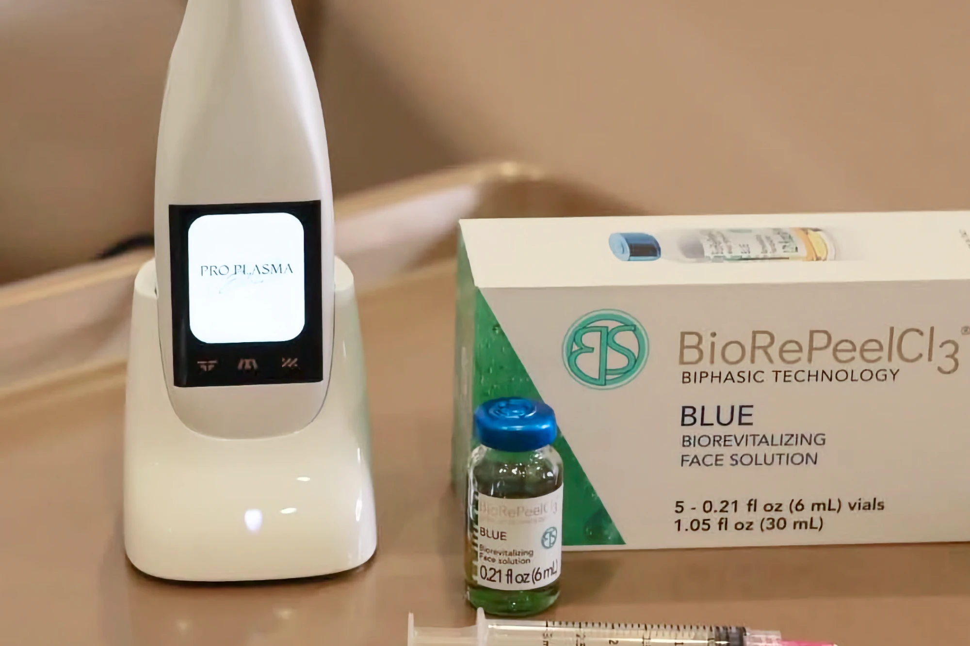 A Pro Plasma handheld device, a box of BioRePeelCl3 revitalizing face solution, a vial, and a syringe are arranged for a cosmetic treatment.